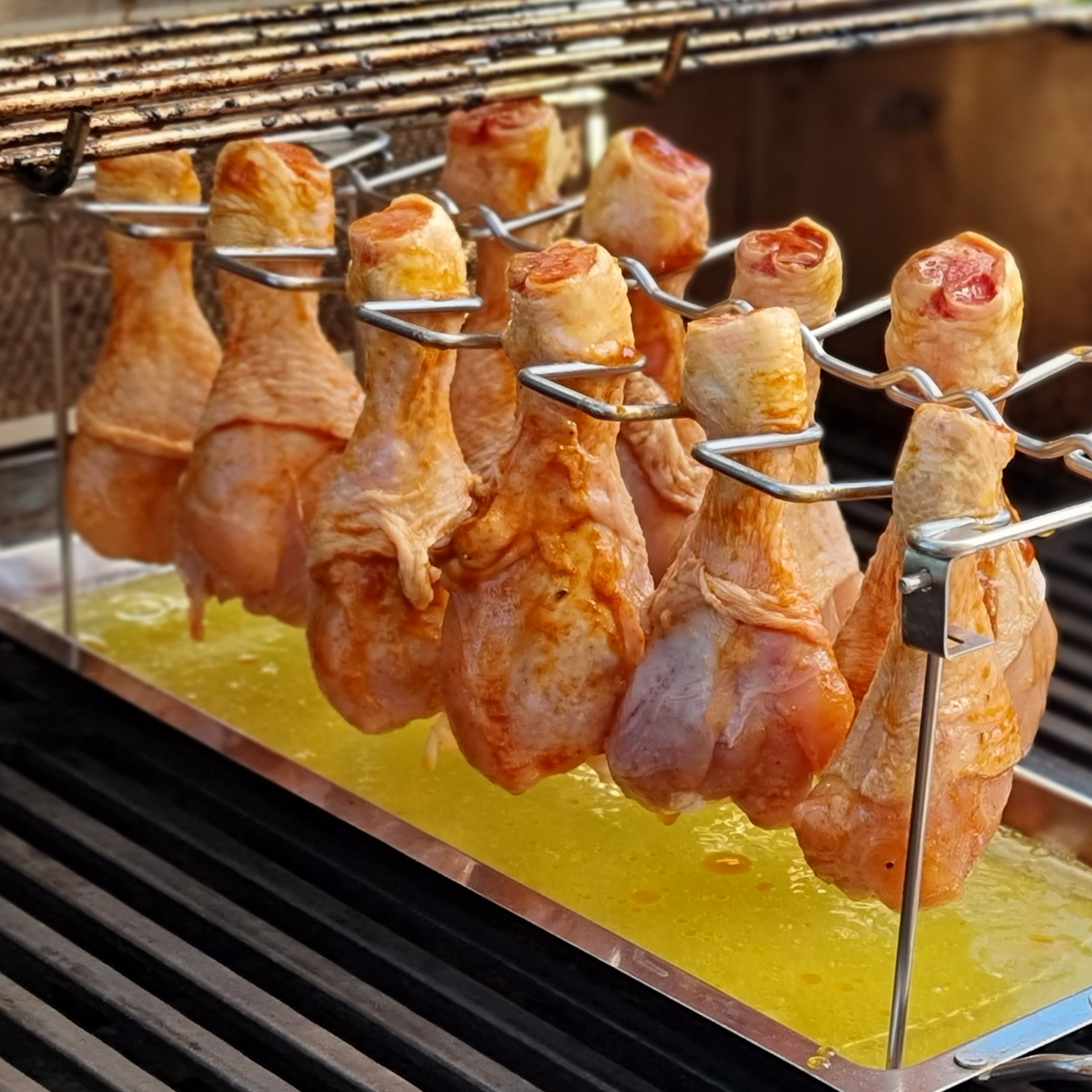 Chicken drumsticks on the holder in the gas grill